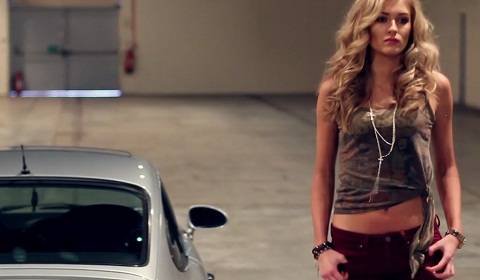 The video follows a classic Porsche 911 driven by tall blond lady